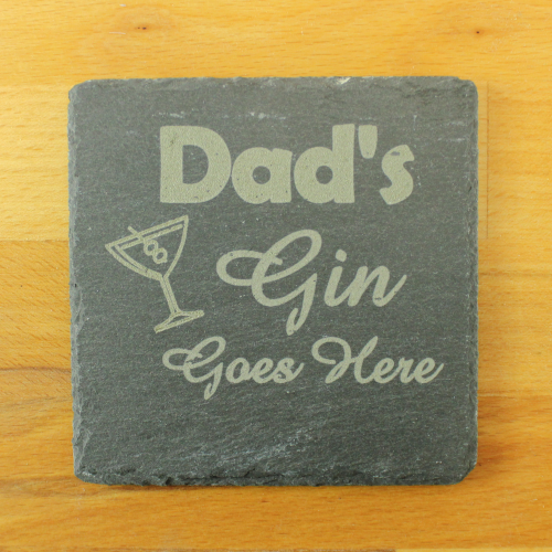 A square slate coaster by The Chuckling Cheese Company with Dad's Gin Goes Here engraved on it.