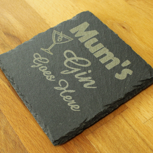 A side view of the square slate coaster by The Chuckling Cheese Company with Mum's gin goes here slogan engraved on it.