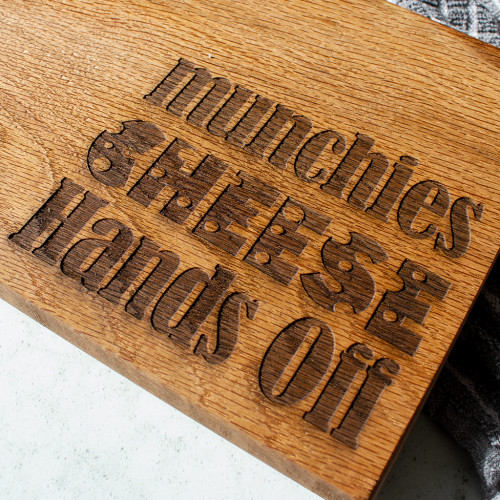 A close up image of the Chuckling Cheese Personalised Name Oak Cheeseboard with Name 'Cheese Hands Off' engraved. Personalise this cheeseboard with your chosen name.