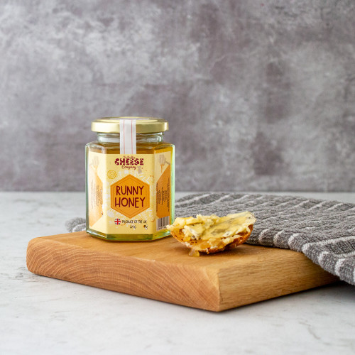 A lifestyle image of a jar of The Chuckling Cheese Company Runny Honey.