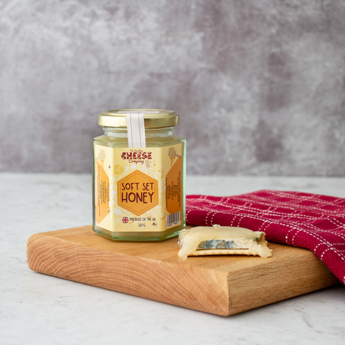 A lifestyleimage of a jar of The Chuckling Cheese Company Soft Set Honey.