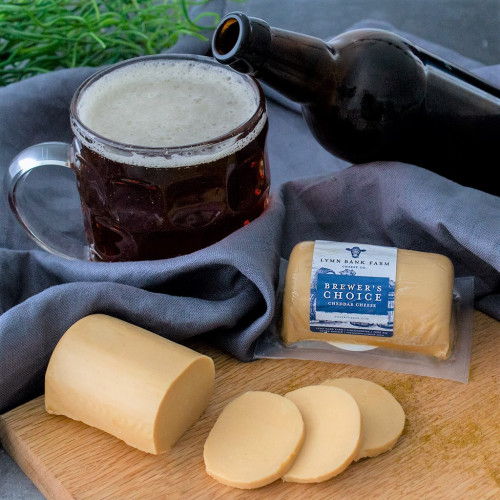 Lifestyle image of the Brewers Choice Cheddar Barrel on a cheeseboard served with a beer