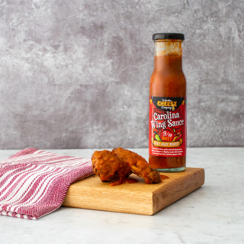 Lifestyle image of a single bottle of Chuckling Carolina Wing Sauce served on chicken wings
