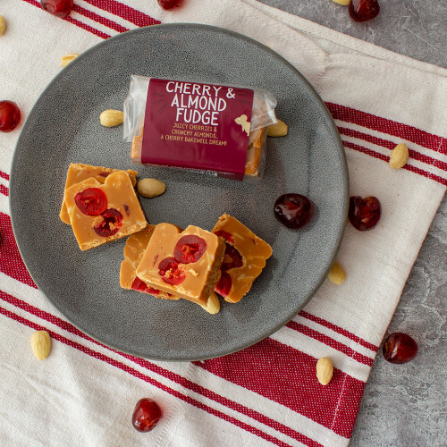 Lifestyle image of a Cherry & Almond Fudge Bar on a plate with glazed cherries and almonds