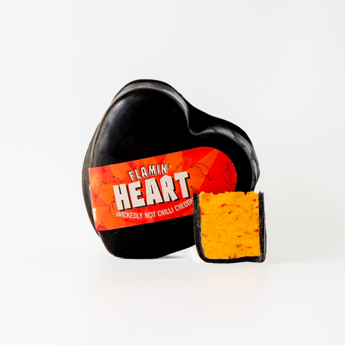 Lifestyle image of the Flamin Heart Cheese Truckle on a cheeseboard with its chutney pairing of caramelised onion chutney.