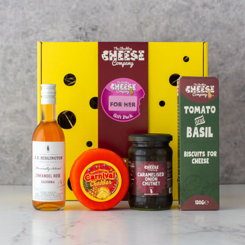 A grey background image of the For Her Gift Box by The Chuckling Cheese Company with cheese, chutney, crackers and wine.