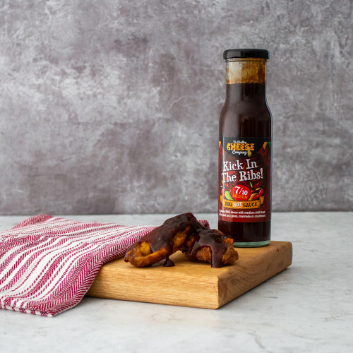 A lifestyle image of a single bottle of Kick in the Ribs Medium Sauce served with chicken wings