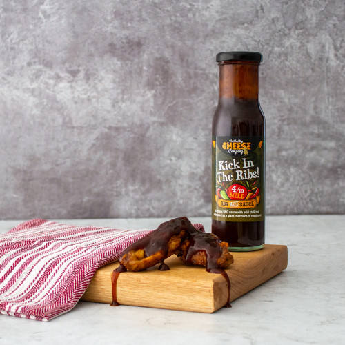 Lifestyle image of a single bottle of Chuckling Kick in the Ribs Mild Sauce served with chicken wings