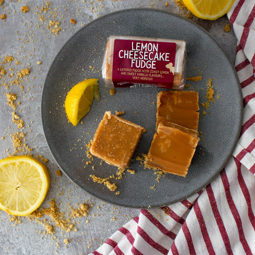 A lifestyle image of a bar of Lemon Cheesecake Fudge decorated with biscuits and lemon