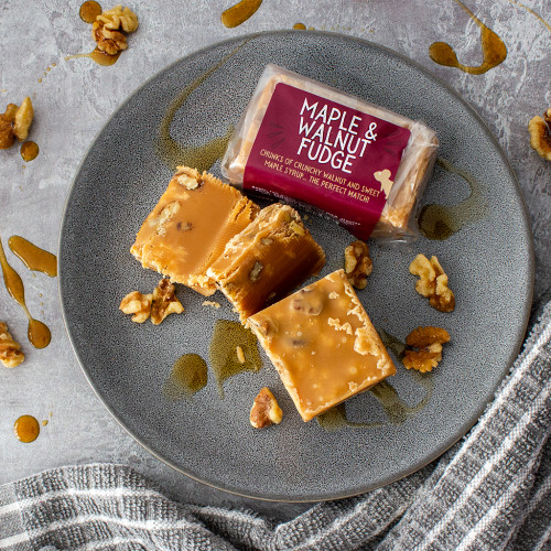 Lifestyle image of the Maple and Walnut Fudge Bar on a plate drizzled with walnuts and maple syrup