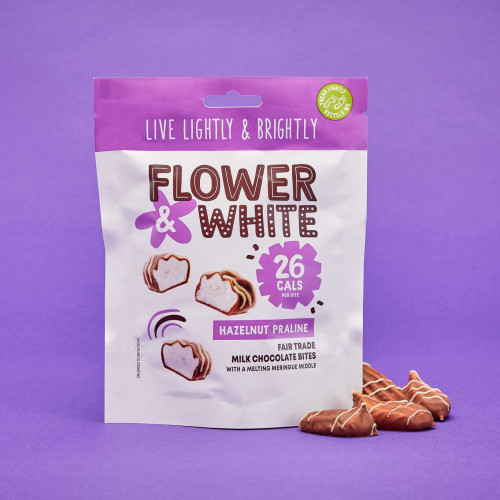 A lifestyle image of a bag of Flower and White Hazelnut Praline Bites.