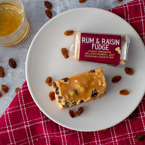Lifestyle image of a rum and raisin fudge bar decorated with raisins and a glass of rum