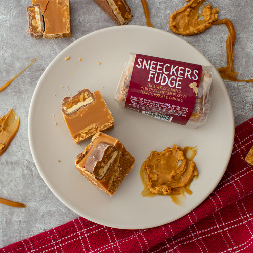 Lifestyle image of a Sneeckers Fudge Bar on a plate drizzled with peanut butter and caramel
