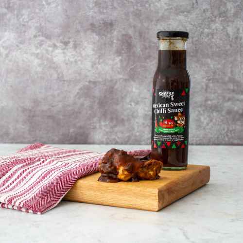 Lifestyle image of single bottle of Chuckling Mexican Sweet Chilli Sauce served with chicken wings