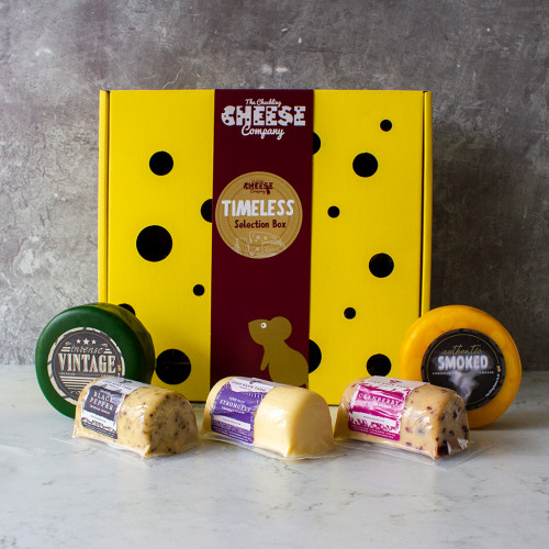 Grey background image of the Timeless Selection Box filled with two cheddar truckles and three cheddar barrels, available to purchase from The Chuckling Cheese Company.