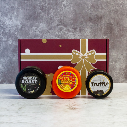 Grey background image of the Cheese Truckle Selection Gift Box including a sunday roast cheddar, carnival cheddar, and a truffle cheddar.